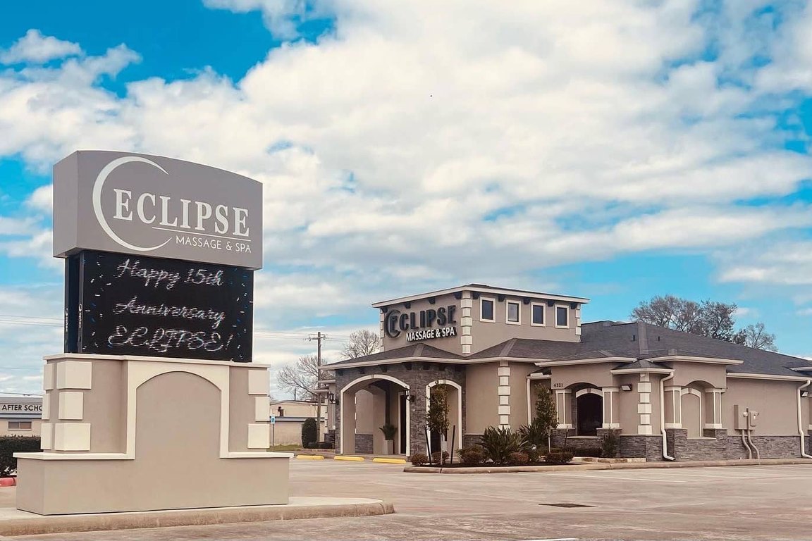 The gray stucco and stacked-stone Eclipse Massage & Spa building and its monument sign under a blue sky