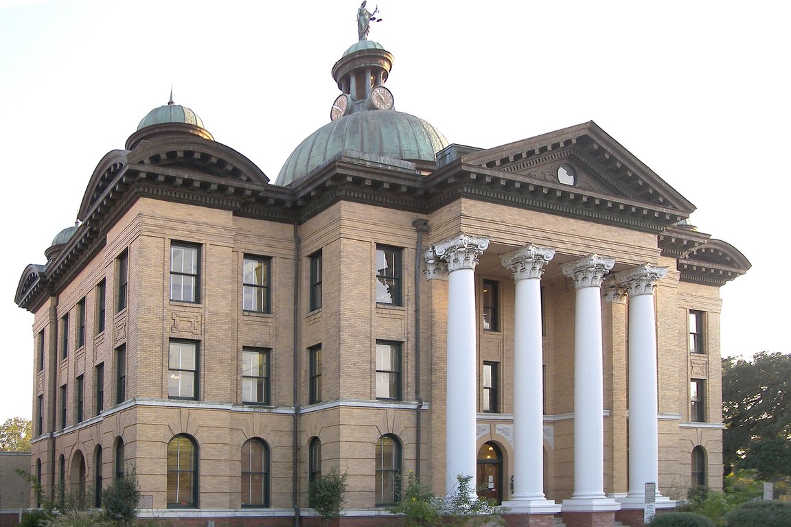 The historic Fort Bend County Courthouse in Richmond, a tan brick building with white columns and copper domes.
