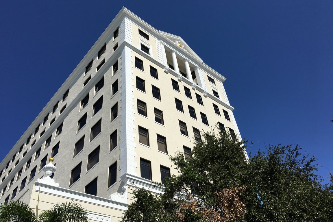 The historic white Comeau Building office tower on Clematis Street against a blue sky.