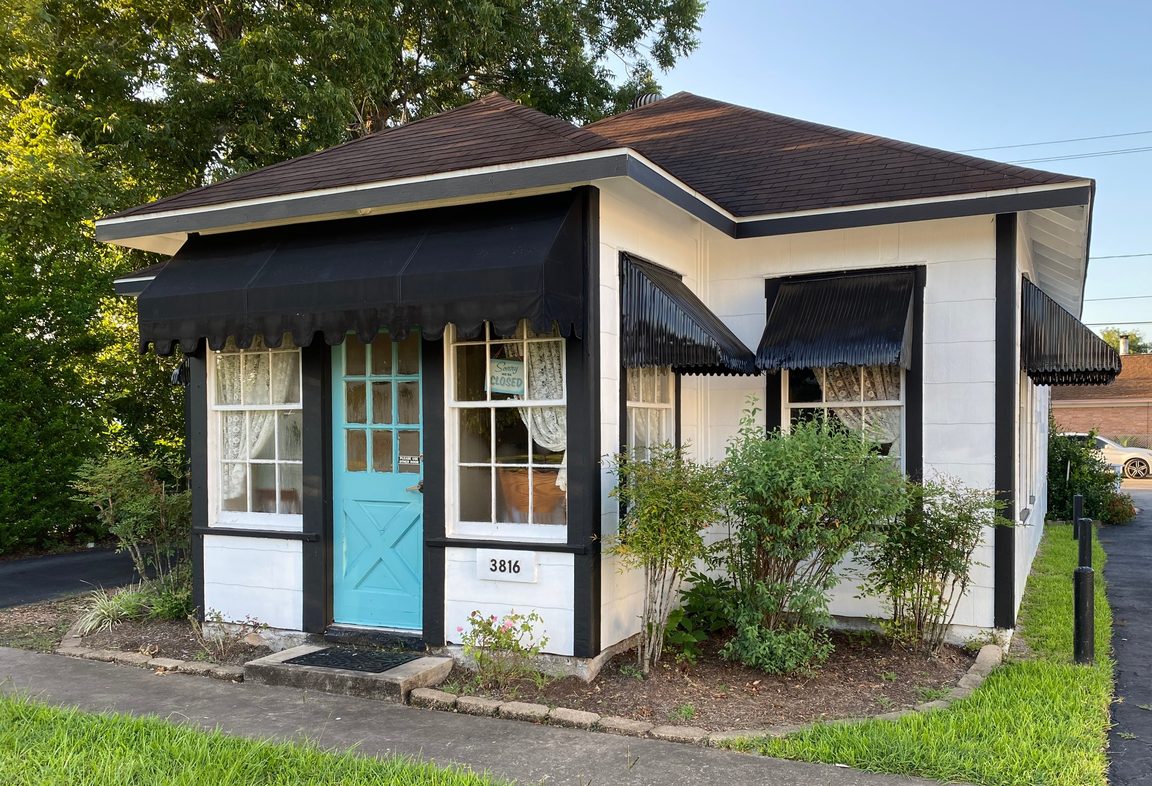 The white frame house with black awnings that holds Four Friends Tea Room