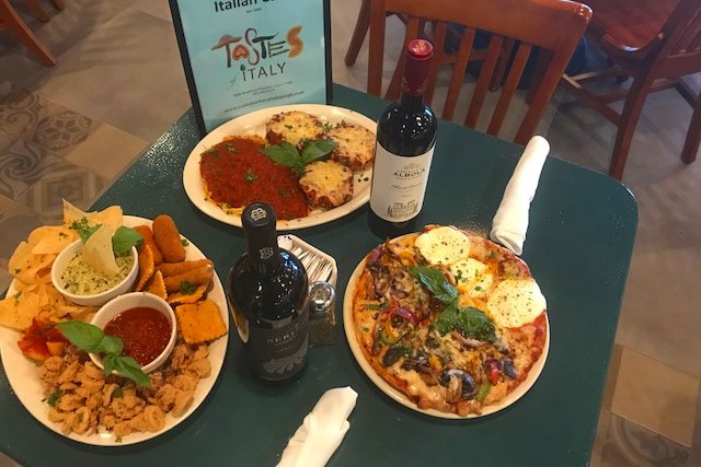 Pizza, chicken parmesan and an appetizer platter beside the Santa Barbara Italian Cafe menu sign