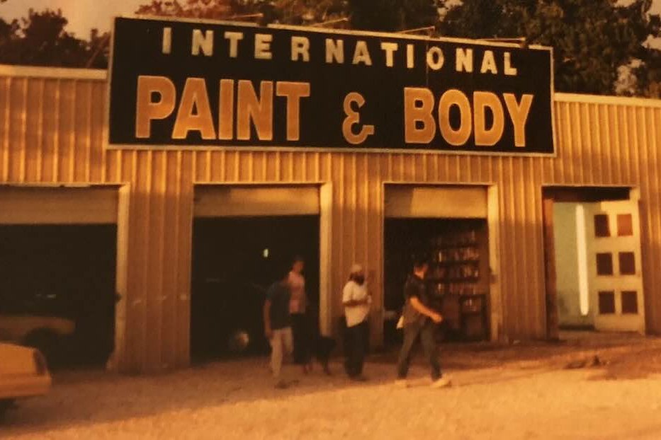 A vintage photo of the original International Paint & Body shop with its big black sign over five bays