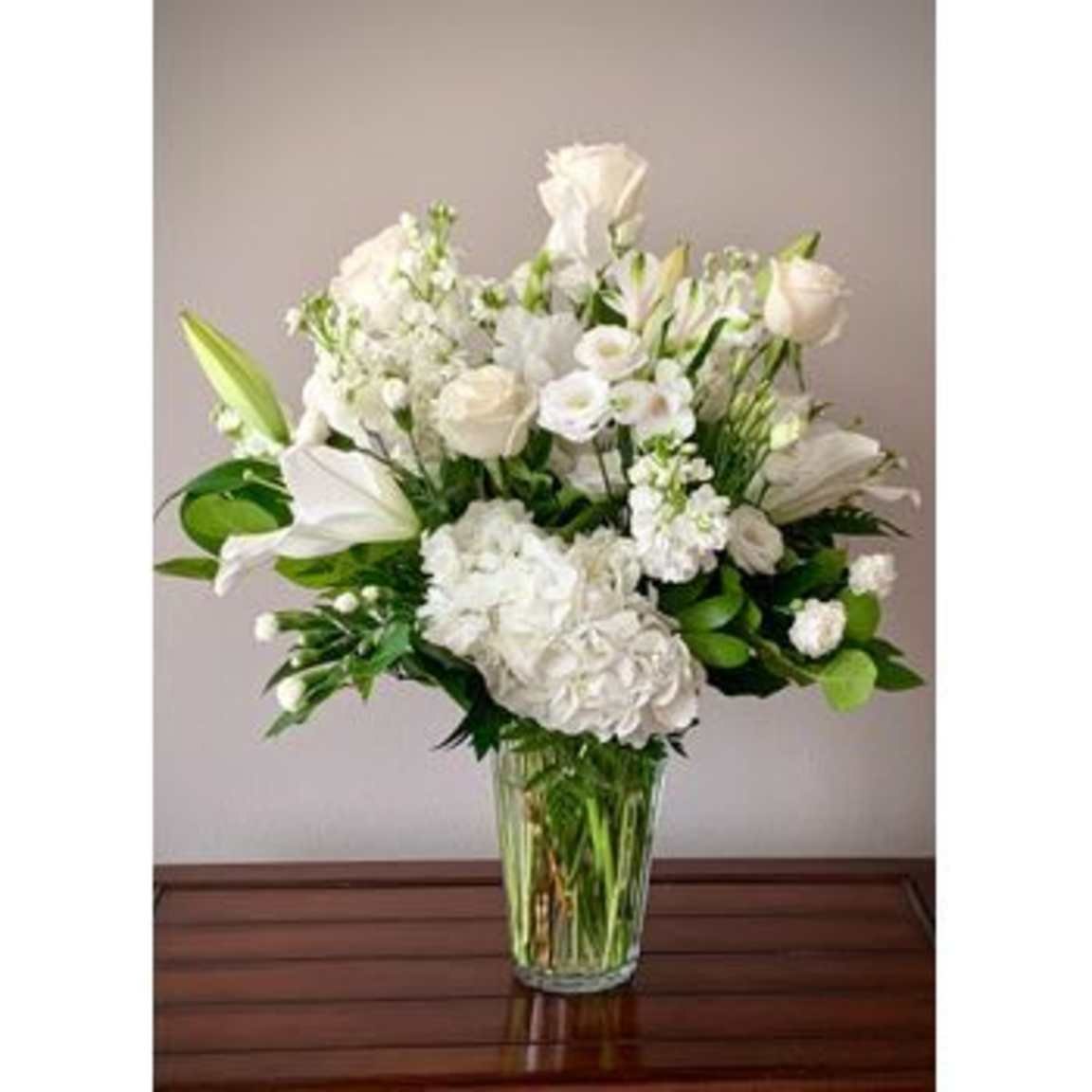 An all-white arrangement of roses, hydrangea and lilies in a cut-glass vase from Nowlin Flower Shop