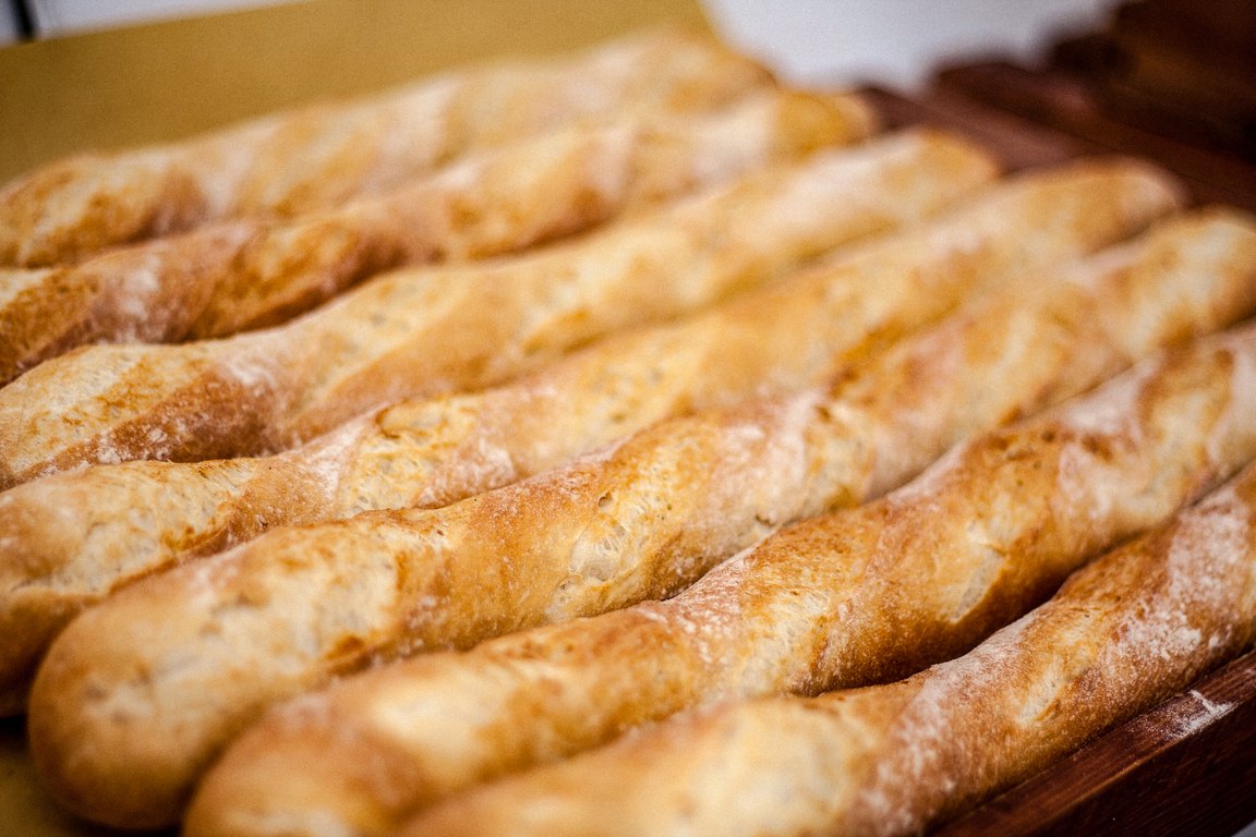 Long golden loaves of fresh bread lined up on a bakery tray